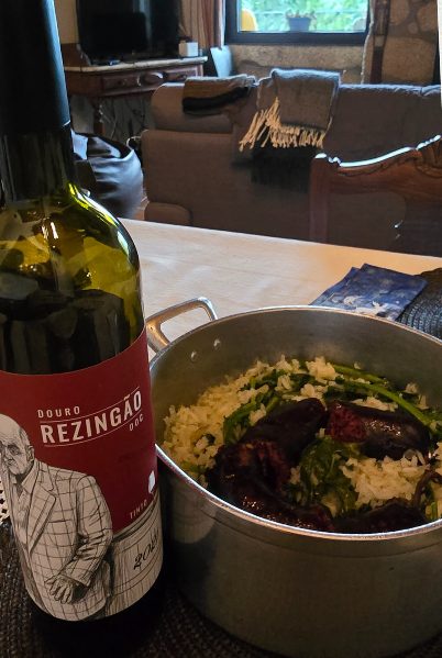 Tacho de arroz com moira na mesa, ao lado de uma garrafa de vinho tinto
