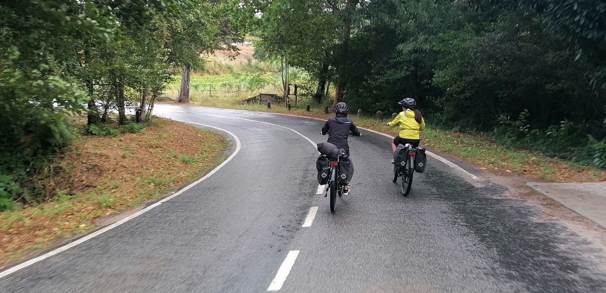 Duas ciclistas numa estrada molhada pela chuva
