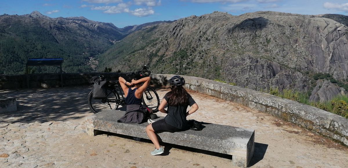 As duas filhas sentadas num banco de pedra num miradouro sobre o vale