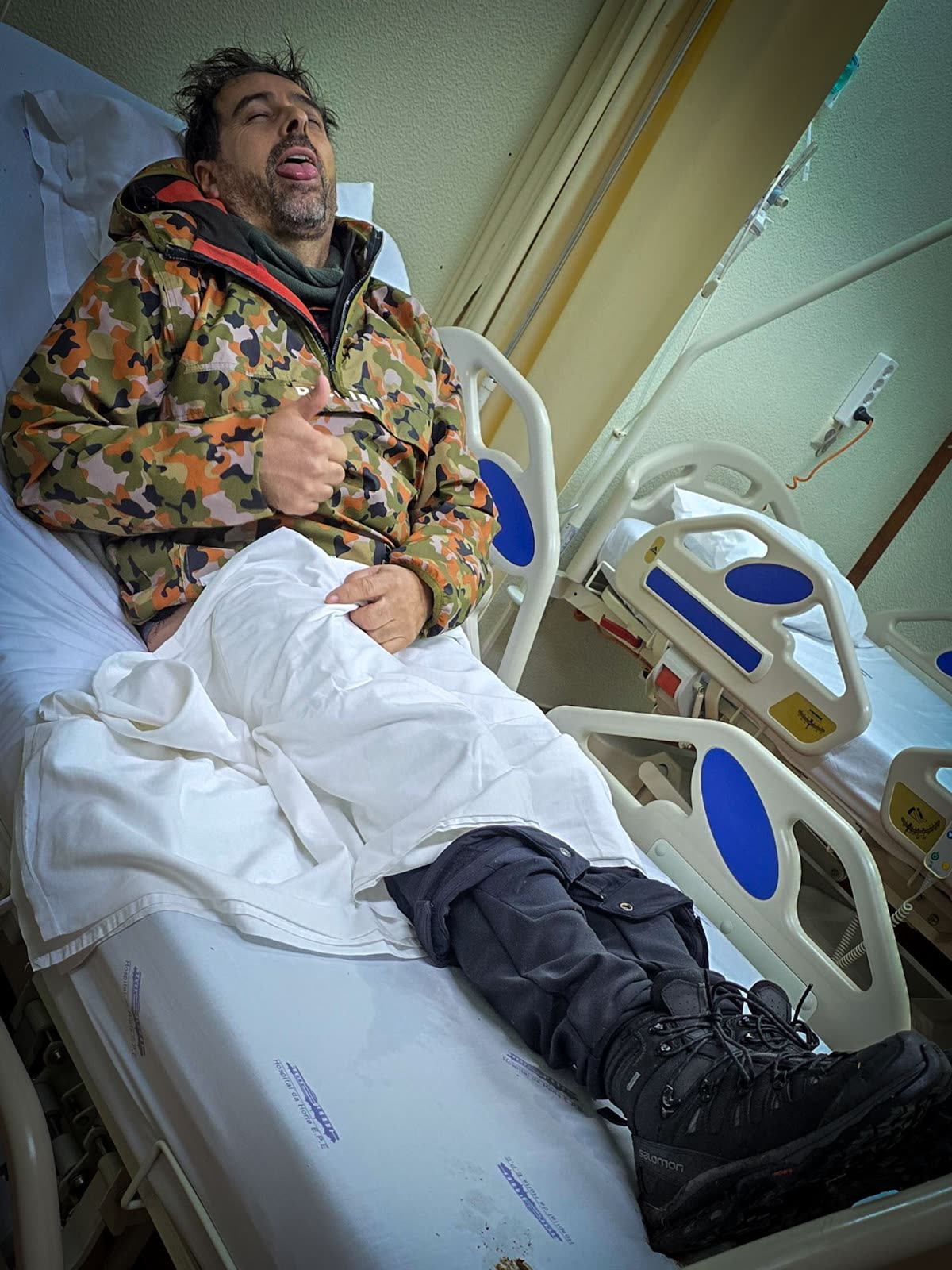 Cláudio after the crash, in bed, thumbs up