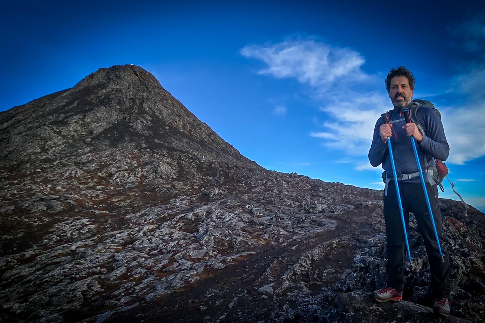 José with trekking poles on the way up, with the summit of Pico behind