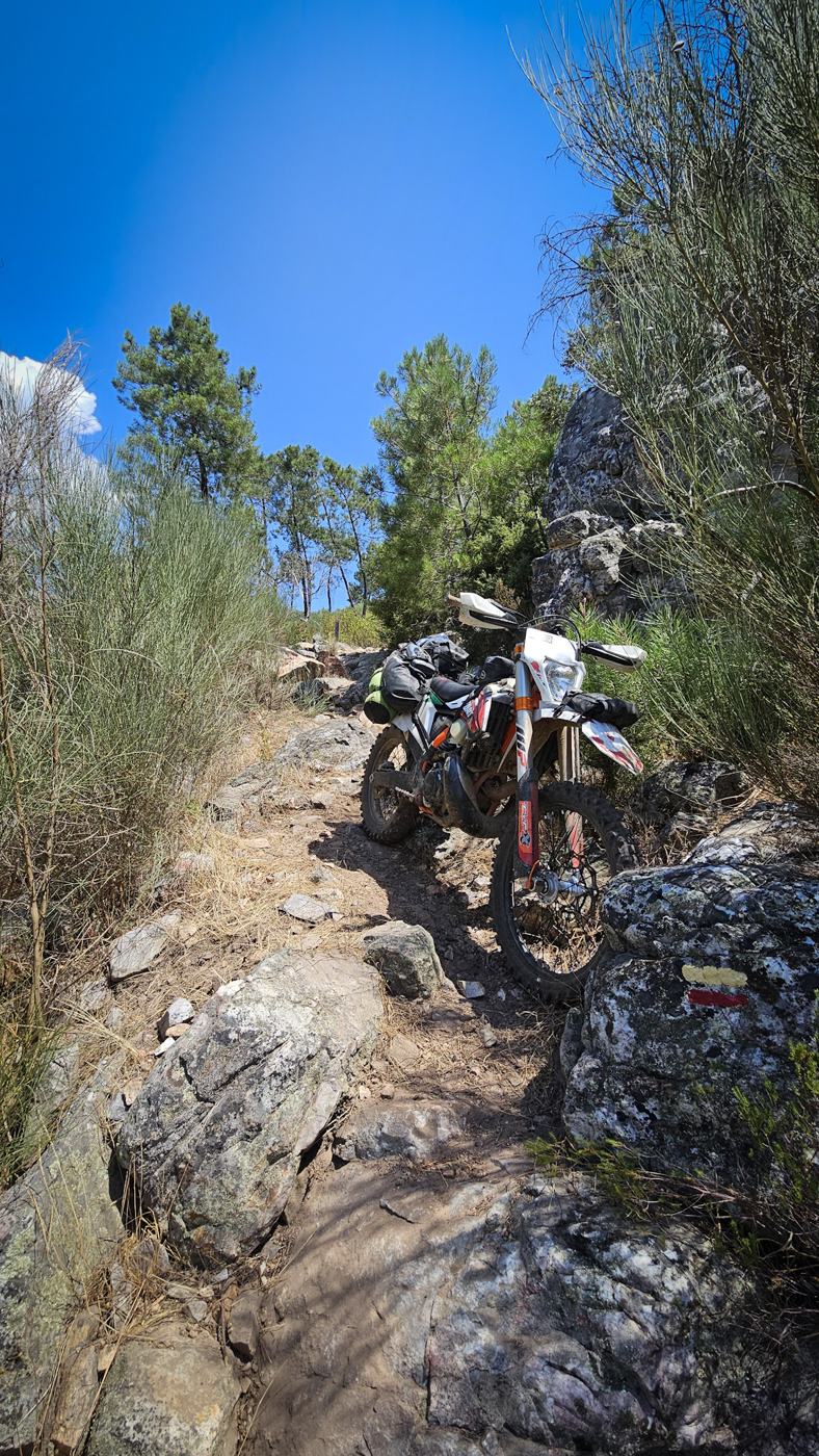 Moto de enduro num trilho rochoso e inclinado