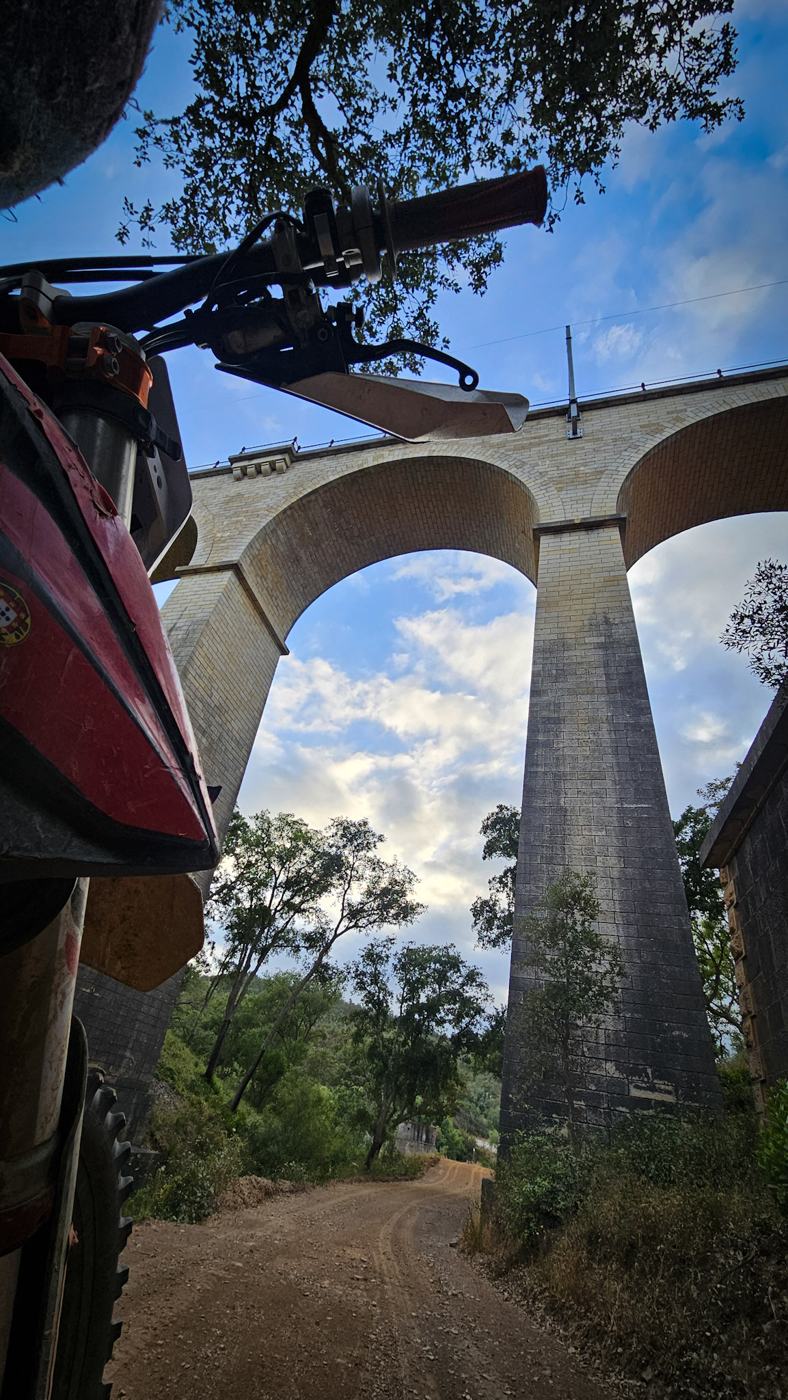 Trilho a passar por baixo de um viaduto de pedra