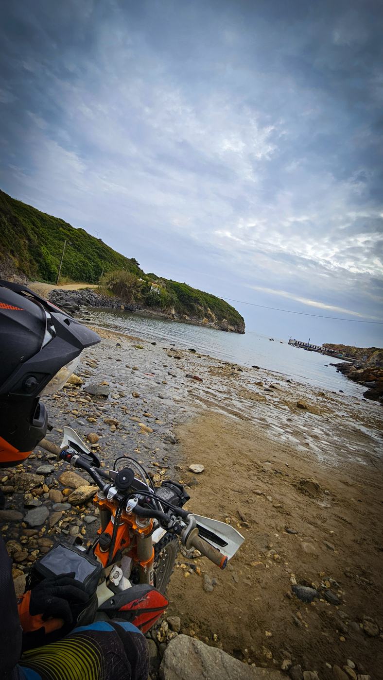 Moto de enduro junto ao mar numa enseada rochosa