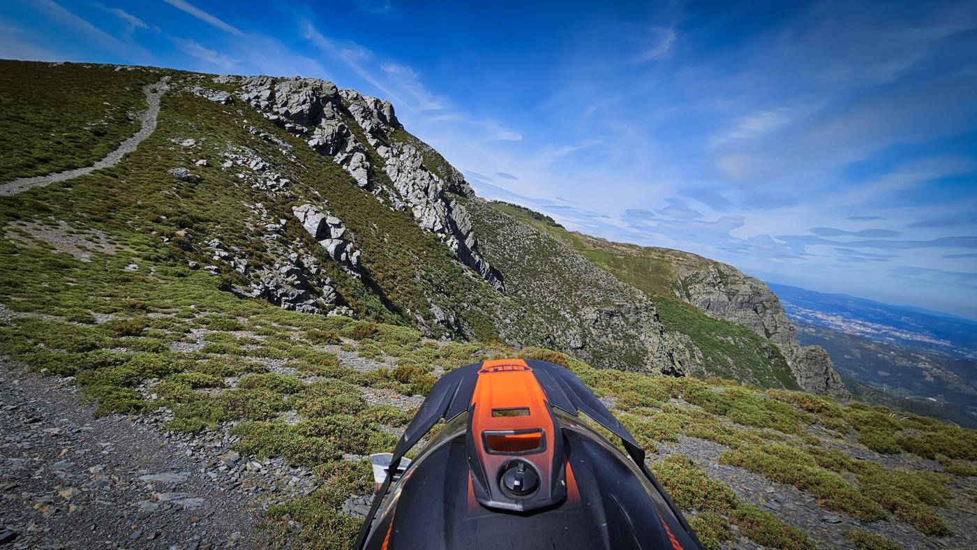 Moto de enduro num trilho de montanha com vista sobre o vale